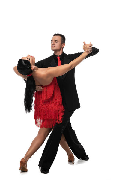 handsome, elegant dancer leading attractive partner while performing tango on white background