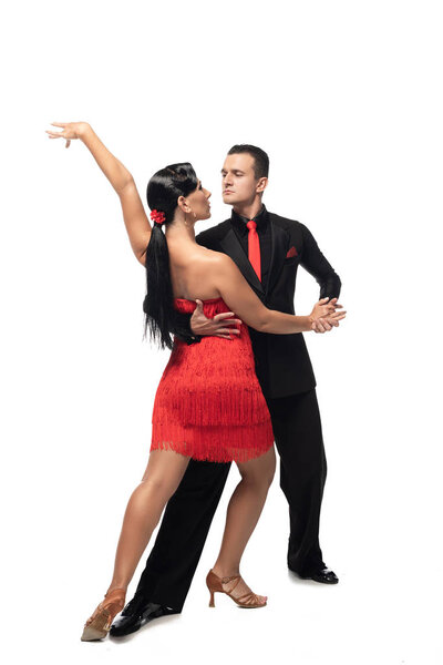 elegant dancers looking at each other while performing tango on white background