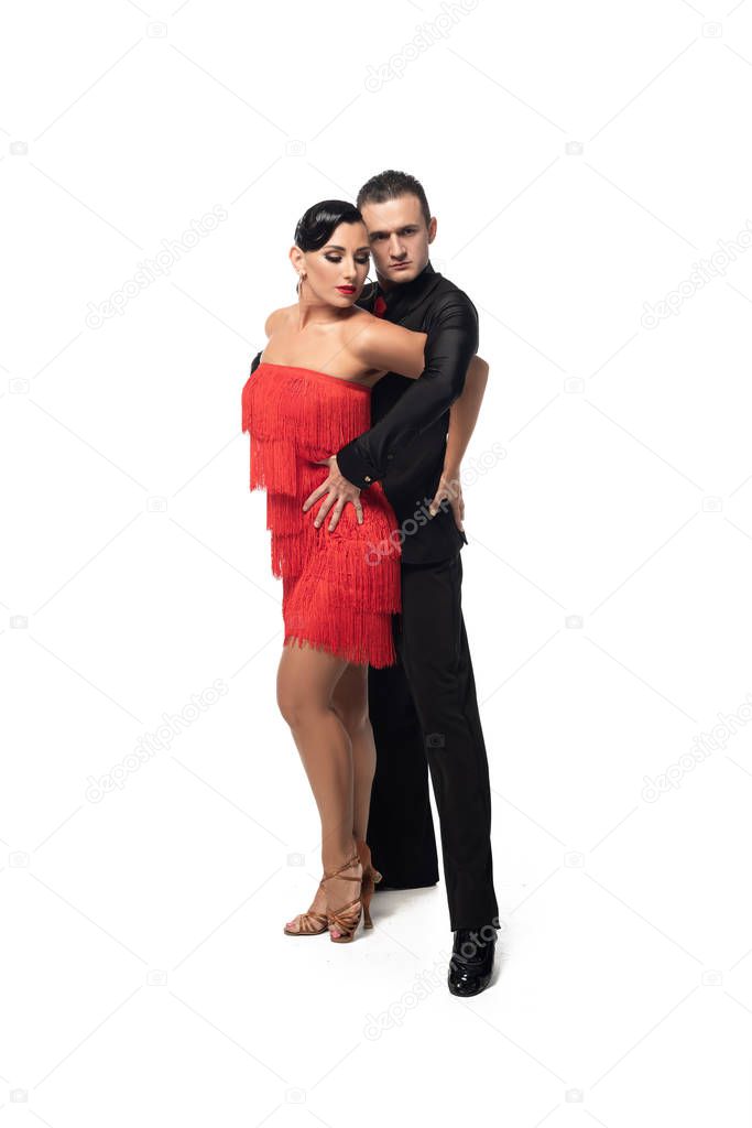 sensual dancer looking at camera while performing tango with attractive partner on white background
