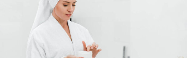 panoramic shot of woman holding container with face cream