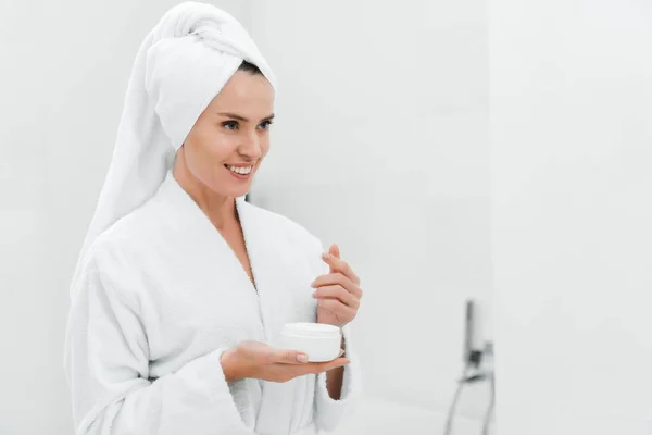 Neşeli Kadın Banyoda Yüz Kremi Konteynırını Tutuyor — Stok fotoğraf