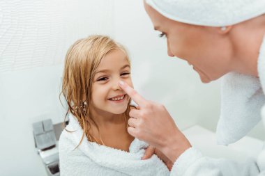 Annenin banyoda mutlu kızının burnuna dokunduğu seçici odaklanma. 