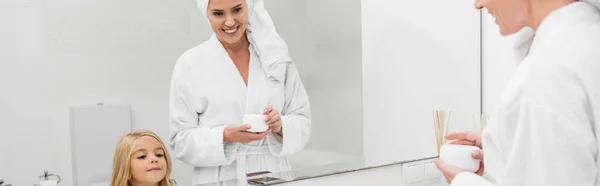 Tiro Panorámico Madre Feliz Sosteniendo Contenedor Con Crema Cosmética Cerca — Foto de Stock