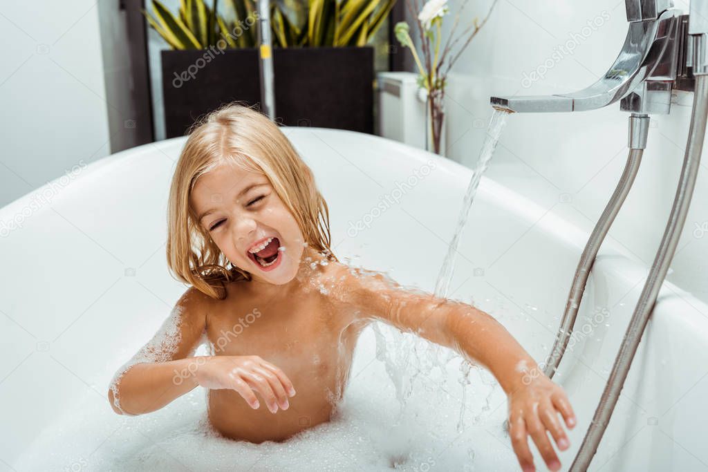 positive naked child taking bath with bath foam at home 
