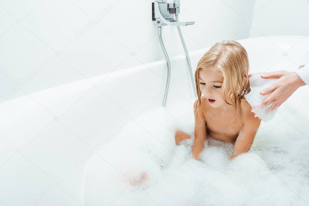 adorable child taking bath near mother at home 