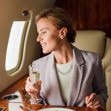 cheerful businesswoman with champagne glass in private jet  clipart