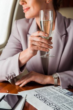 Özel uçakta şampanya bardağı tutan iş kadını görüntüsü. 