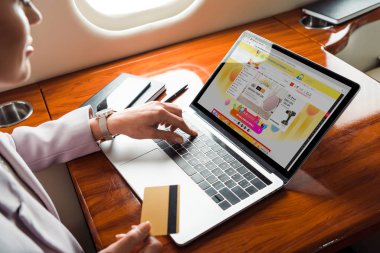 Özel uçakta internetten alışveriş yaparken dizüstü bilgisayar kullanan iş kadını görüntüsü 