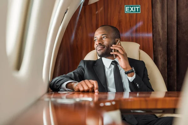 英俊潇洒的非洲商人在私人飞机上用智能手机交谈的选择性焦点 — 图库照片