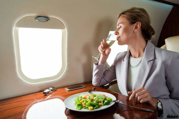 Üzletasszony Pezsgőt Iszik Közel Ízletes Saláta Magánrepülőn — Stock Fotó
