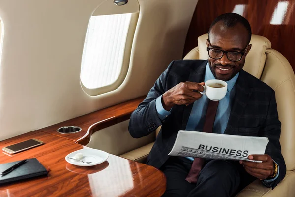 Empresário Afro Americano Alegre Óculos Segurando Jornal Negócios Xícara Avião — Fotografia de Stock