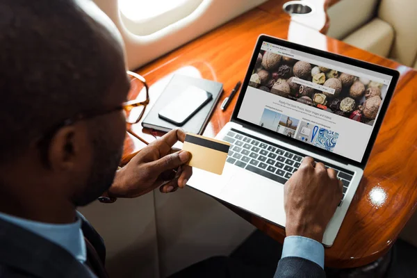 非洲裔美国商人在笔记本电脑附近持信用卡 在私人飞机上有存款照片网站的选择性焦点 — 图库照片