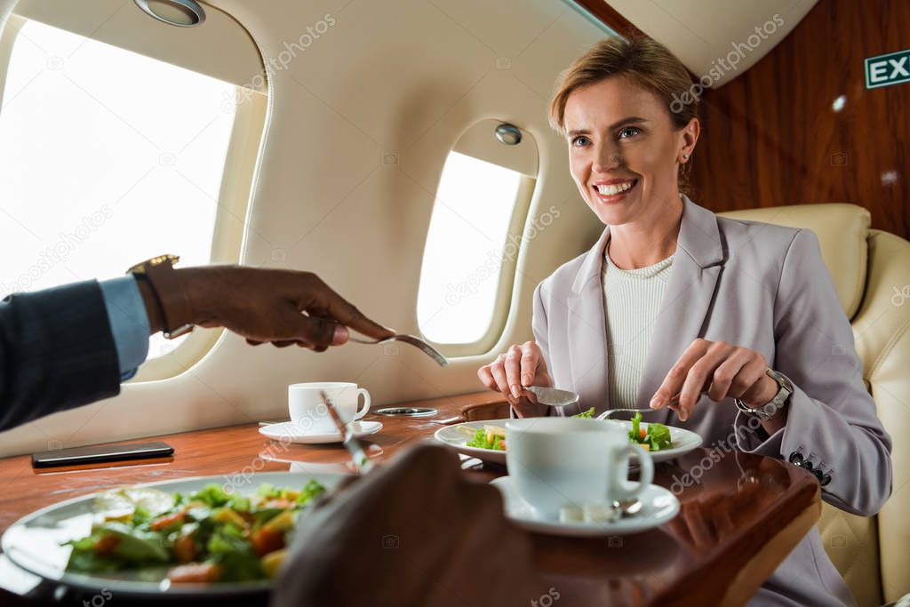selective focus of happy businesswoman near african american businessman and salads 