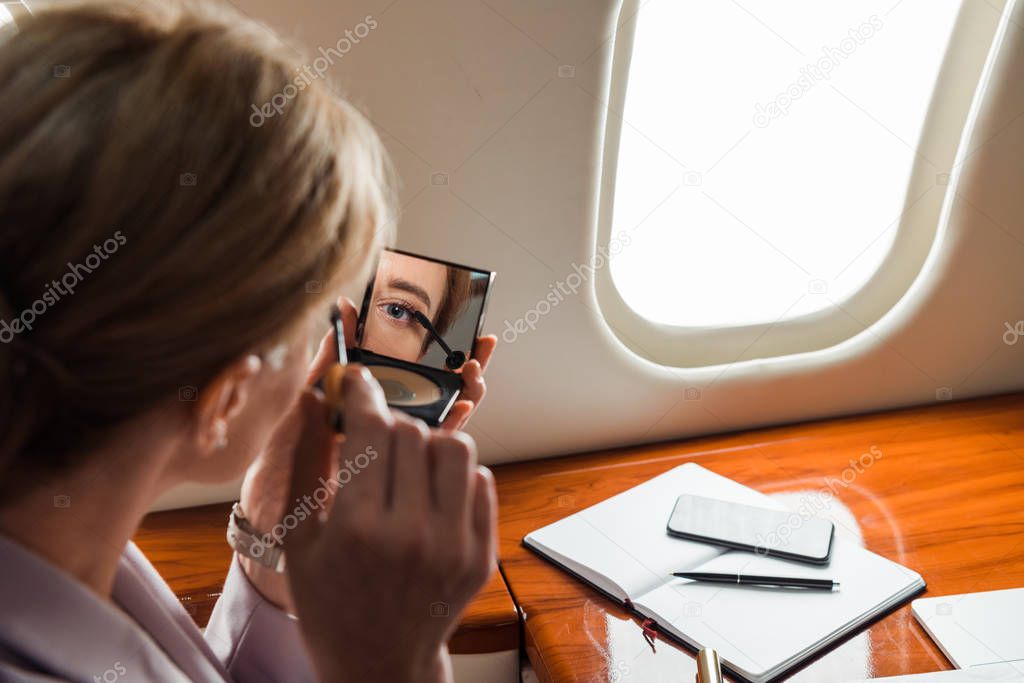 selective focus of businesswoman apply mascara in private plane 