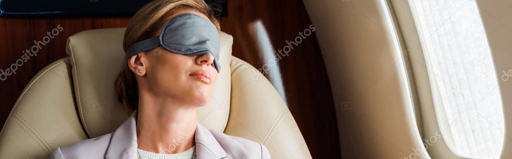 panoramic shot of businesswoman with sleeping mask sitting in private plane 