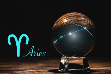 crystal ball with constellation near Aries zodiac sign on wooden table isolated on black clipart
