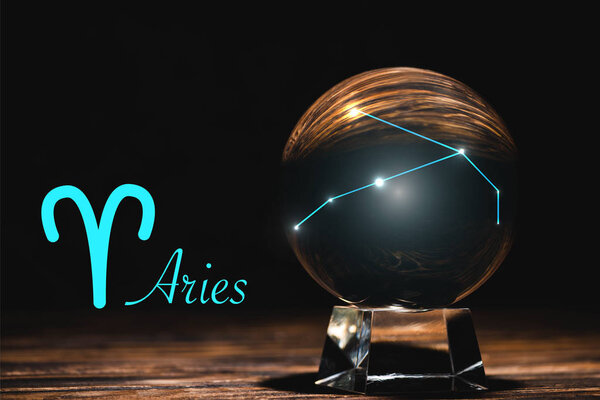 crystal ball with constellation near Aries zodiac sign on wooden table isolated on black