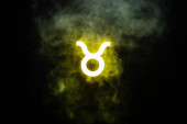 gelb beleuchtetes Taurus Tierkreiszeichen mit Rauch auf Hintergrund