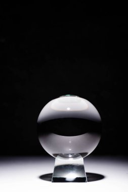 crystal ball on white surface on black background clipart