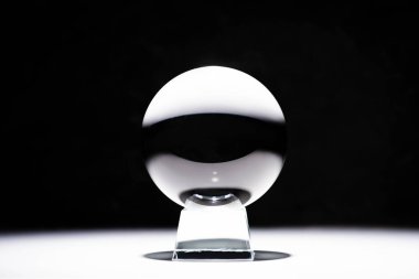 crystal ball on white surface on black background clipart