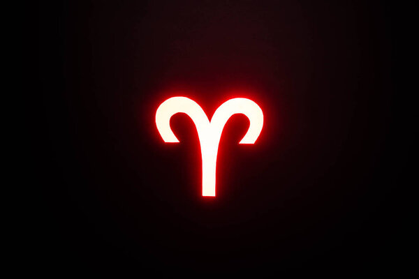 red illuminated Aries zodiac sign on black background