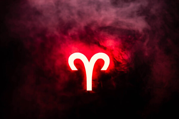 red illuminated Aries zodiac sign with smoke on background
