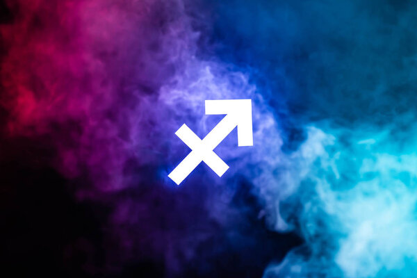 blue illuminated Sagittarius zodiac sign with colorful smoke on background
