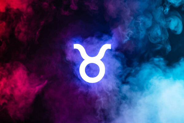 blue illuminated Taurus zodiac sign with colorful smoke on background