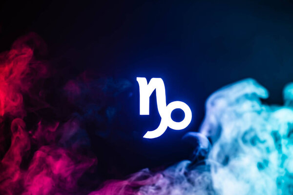 blue illuminated Capricorn zodiac sign with colorful smoke on background