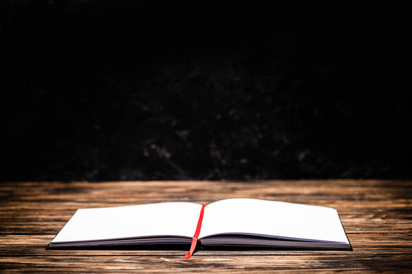 open book with red bookmark on wooden table