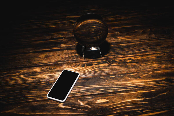 crystal ball with smartphone on wooden table