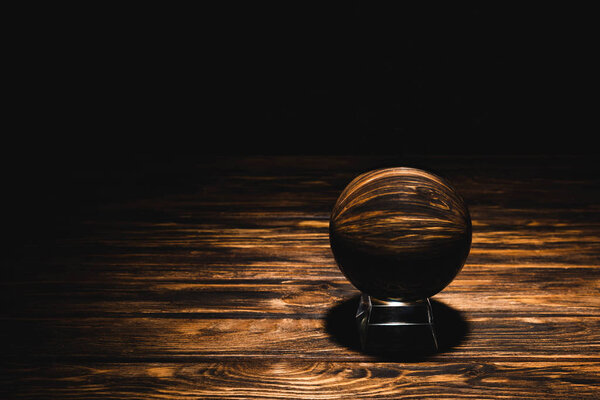 crystal ball on wooden table on black background