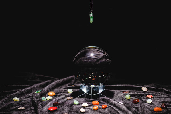 fortune telling stone above crystal ball on black velvet cloth isolated on black