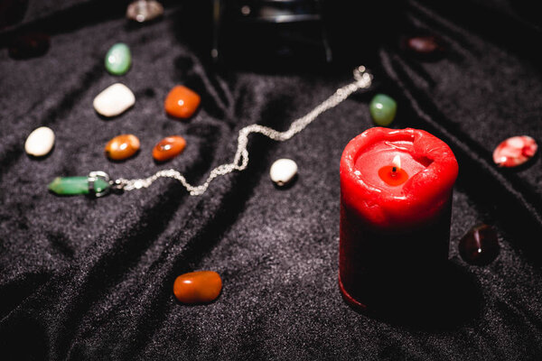 selective focus of fortune telling stones and candle on black velvet cloth