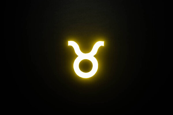 yellow illuminated Taurus zodiac sign isolated on black
