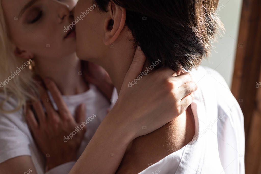 Selective focus of young couple hugging and kissing in sunlight 