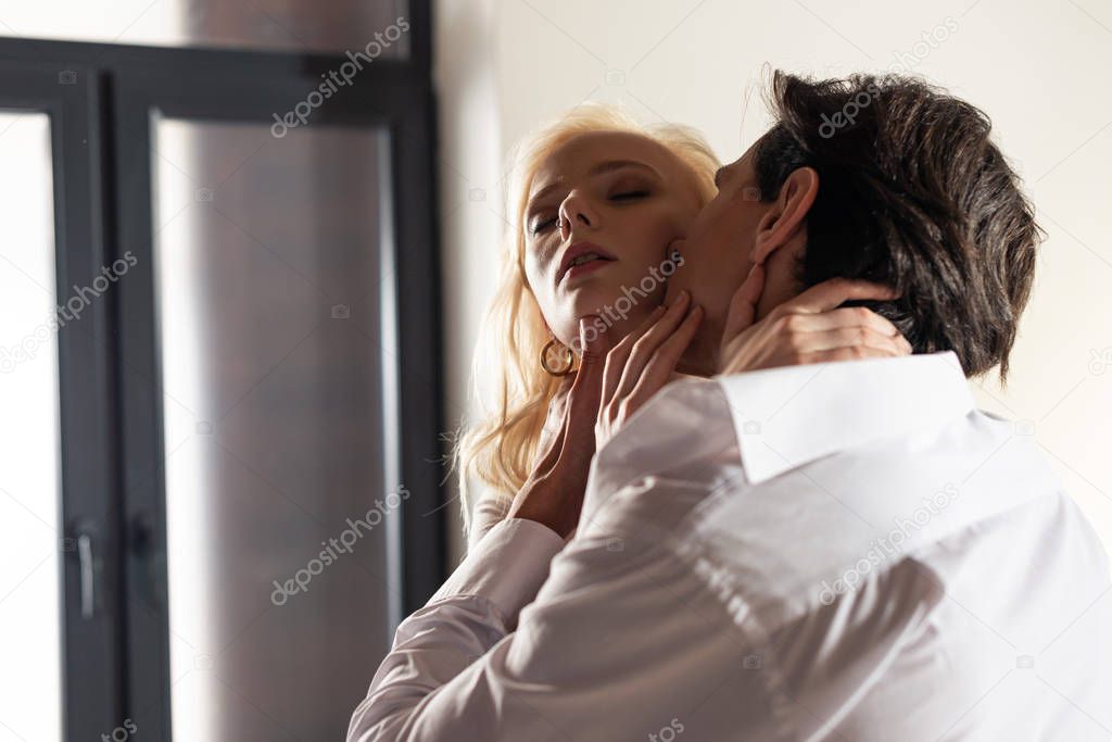 Man embracing and kissing beautiful blonde woman at home
