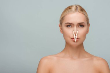beautiful and naked young woman with wooden pin on nose isolated on grey  clipart