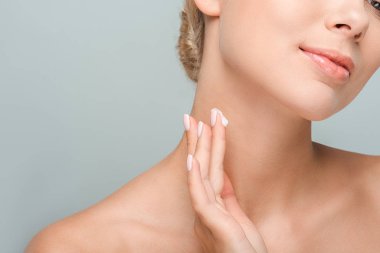 cropped view of woman applying cosmetic cream on neck isolated on grey  clipart