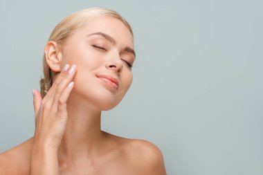 Gri renkte izole edilmiş temiz yüzlere dokunan mutlu kadın. 