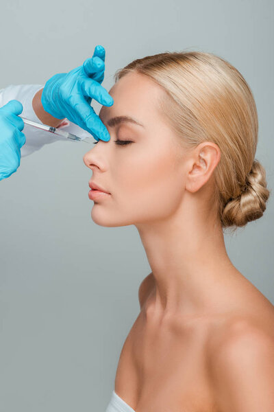 cropped view cosmetologist making beauty injection to beautiful woman isolated on grey