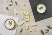 Top view of tzatziki sauce on boards with ingredients on stone background