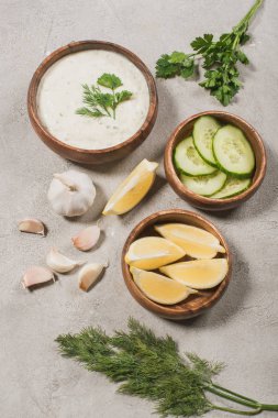 Traditional greek tzatziki sauce from yogurt, cucumber with lemon and garlic on stone background clipart