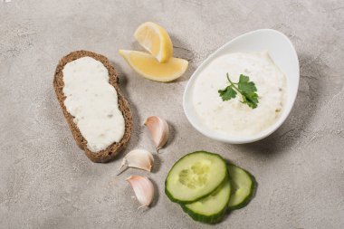 Üst görünüm tzatziki sosu ham malzemeler ve taş zemin üzerinde ekmek