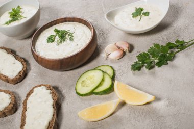 Ev yapımı tzatziki sosu ve taş yüzeyinde taze malzemeler.