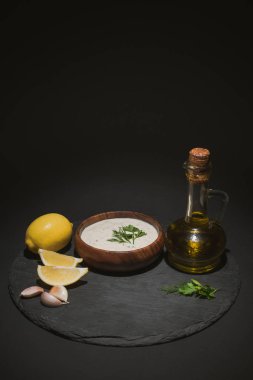 Geleneksel Yunan tzatziki sosu zeytin yağı ve siyah zemin üzerindeki malzemeler
