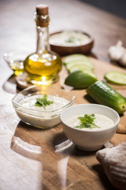 Tabaklarda Tzatziki sosu, malzemeler ve ahşap masada zeytin yağı. 