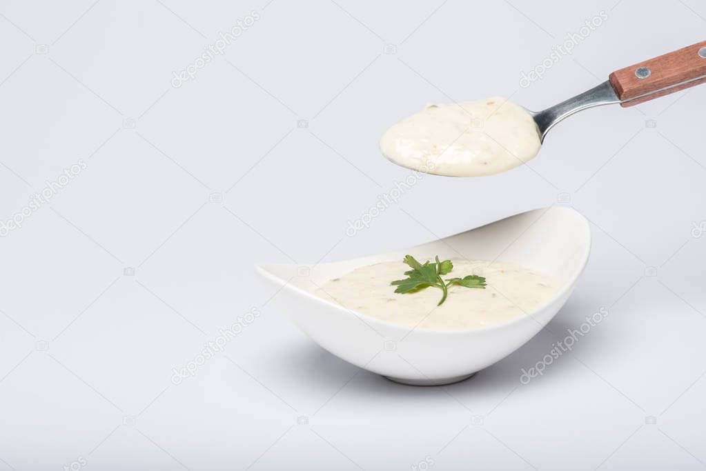 Homemade tzatziki sauce with spoon on white background