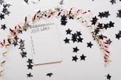 shora pohled na notebook s 2020 seznam cílů s prázdnými body v blízkosti dekorativní, lesklé hvězdy a hadovité na bílém stole