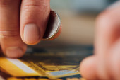 zblízka pohled na stříbrnou minci v ruce hazardního hráče v blízkosti poškrábaný los
